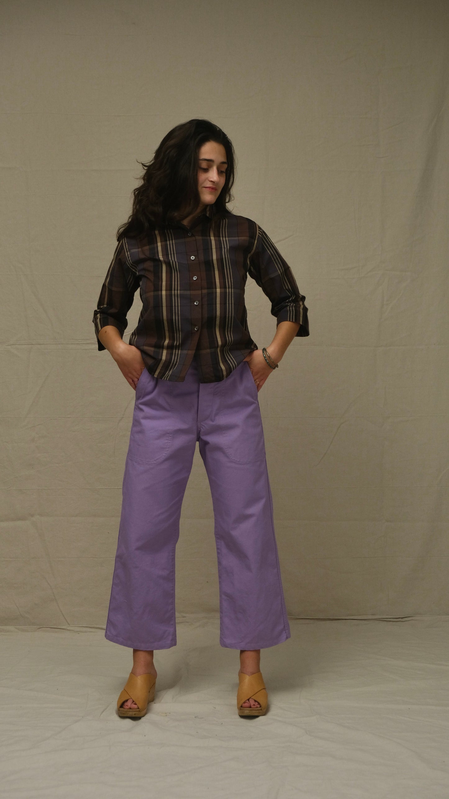 Woman wearing a plaid shirt and purple pants against a plain background