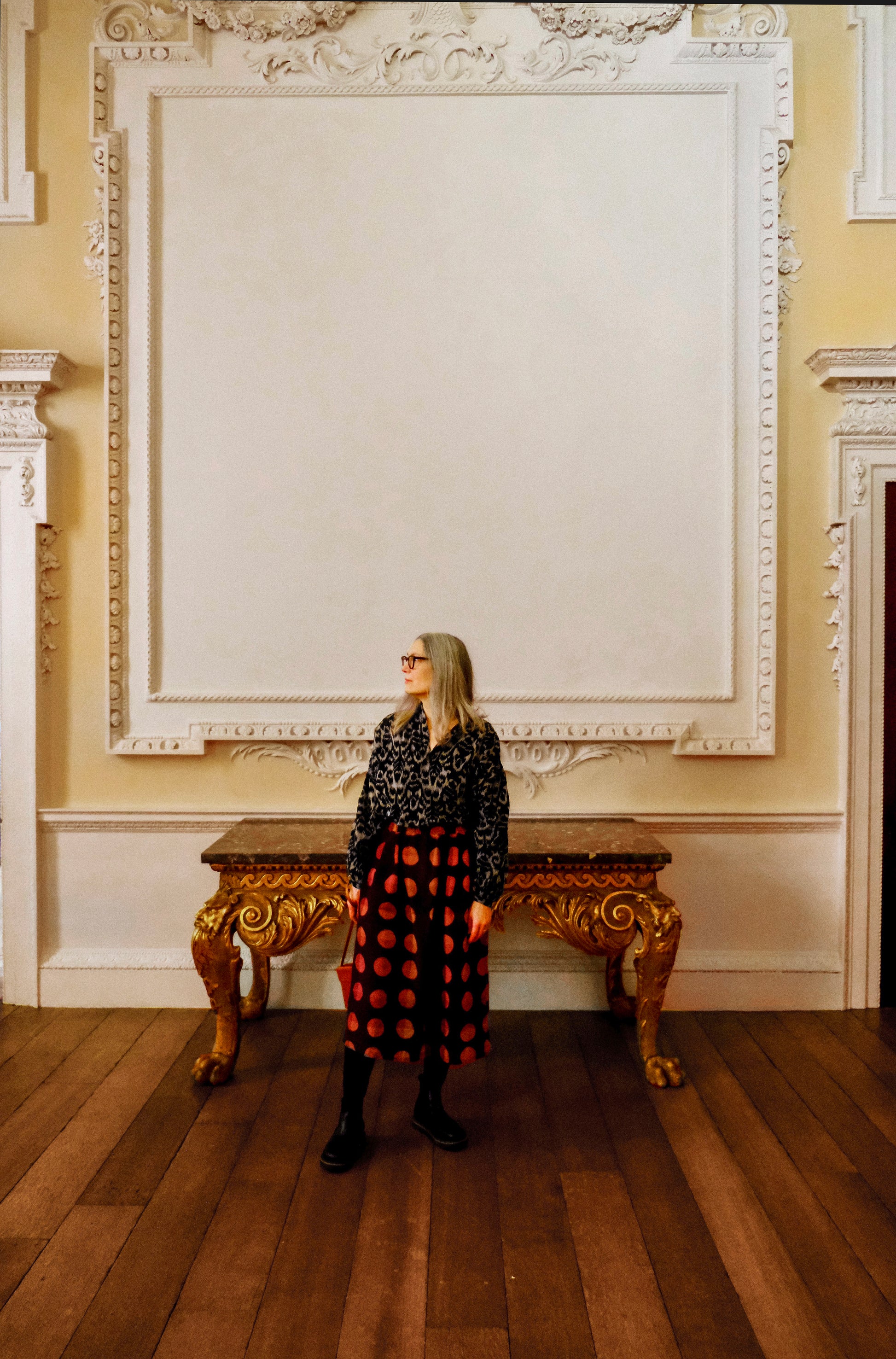 Woman wearing a black ikat peasant blouse standing in an elegant room with ornate decor