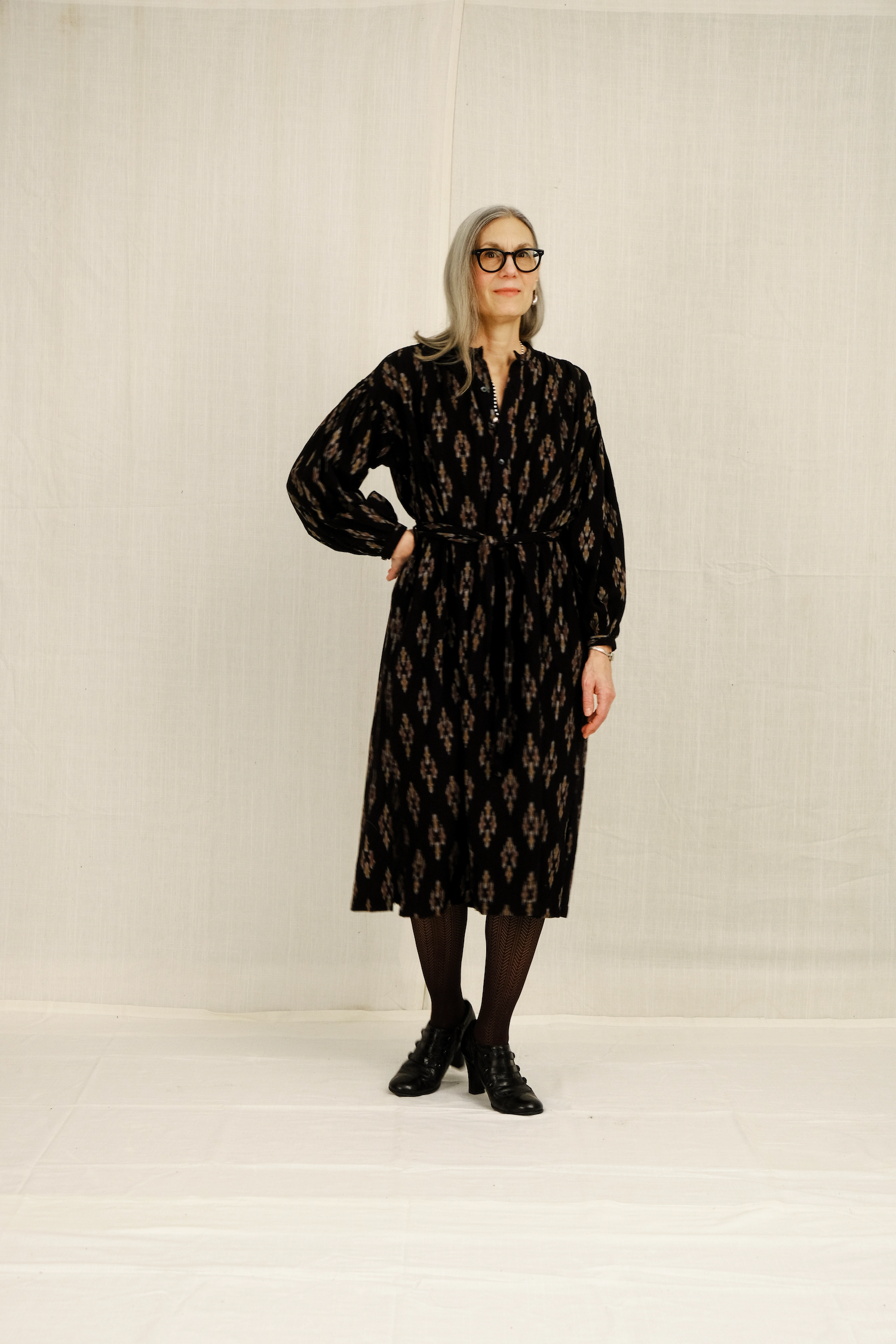 Woman wearing a black patterned dress against a plain background