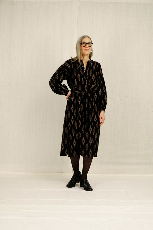 Woman wearing a black patterned dress against a plain background