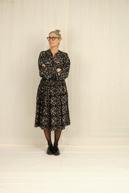 Person wearing a black ikat peasant blouse and belle skirt against a white background