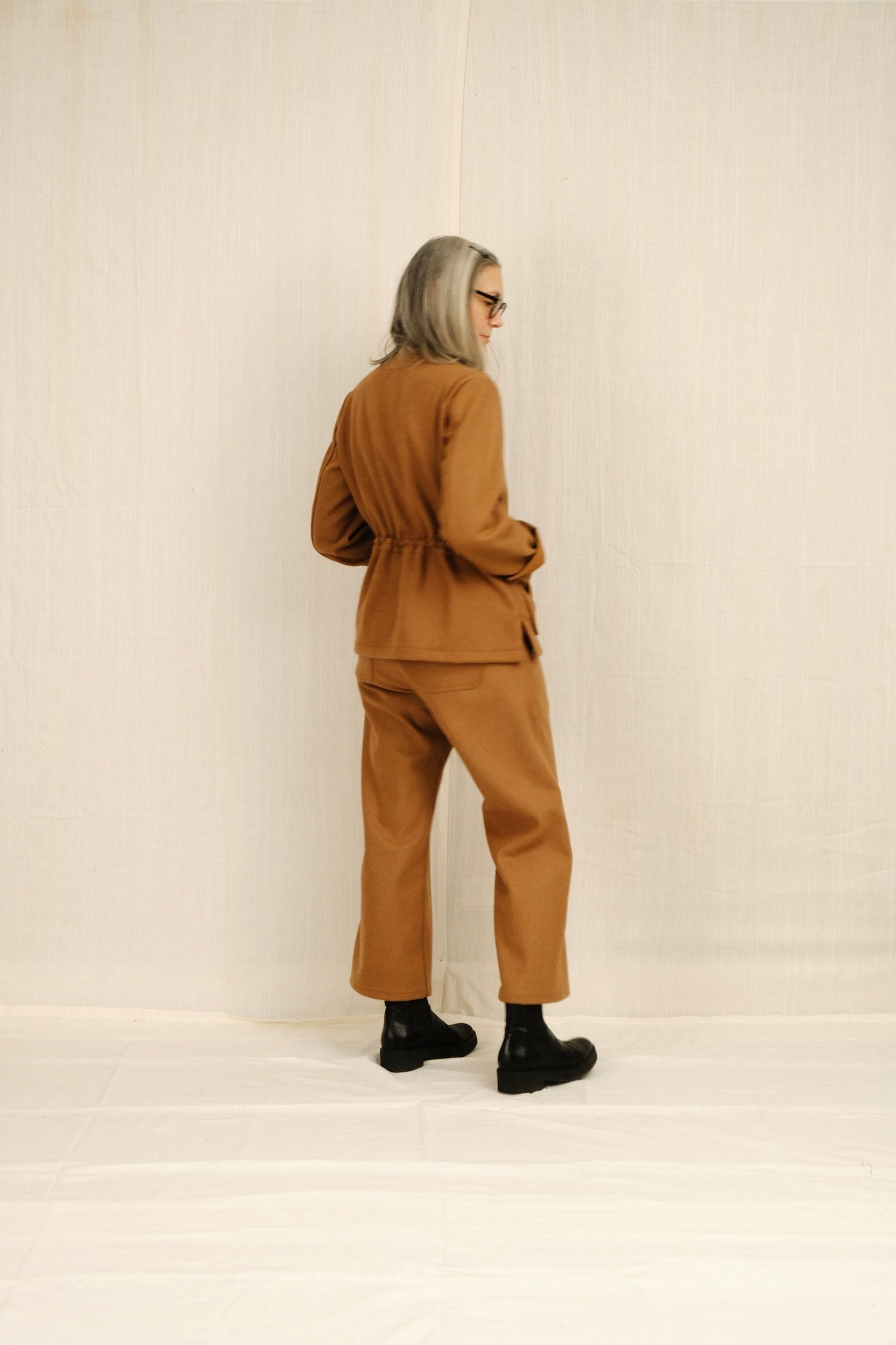 Person wearing a brown outfit standing against a plain background