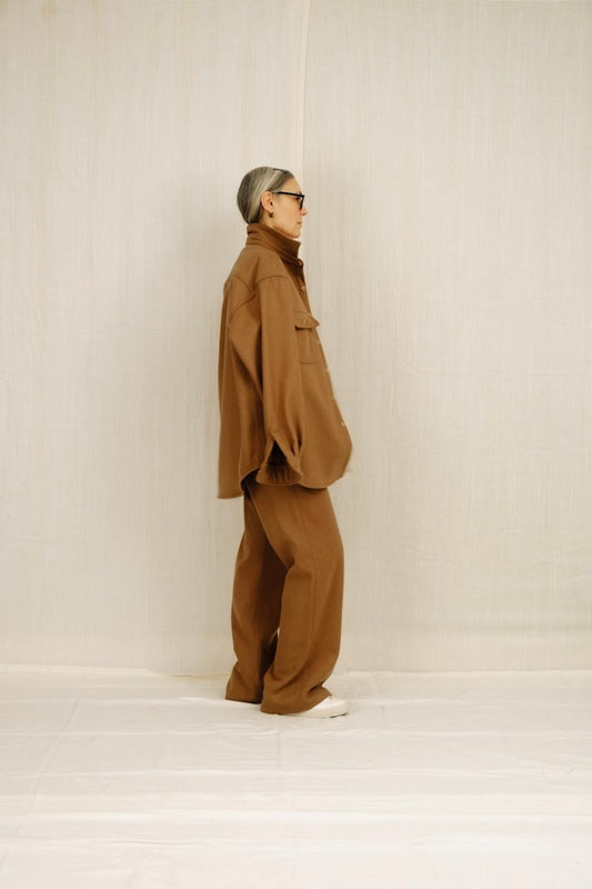 Person wearing a brown outfit standing against a white background
