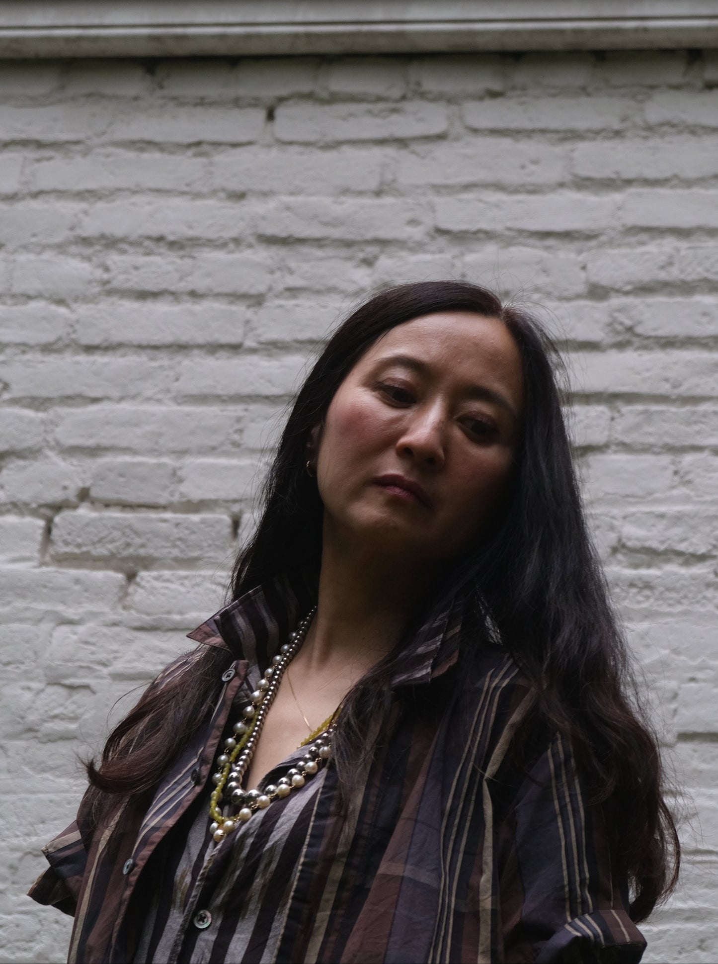 Woman standing against a white brick wall