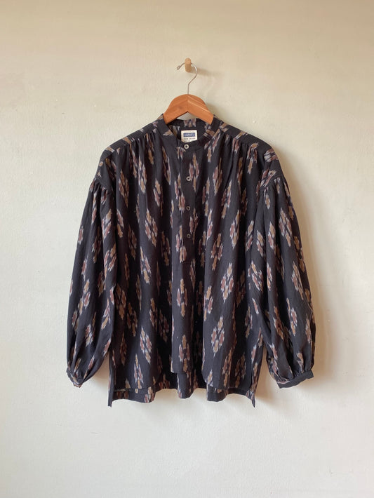 Patterned shirt on a hanger against a plain background