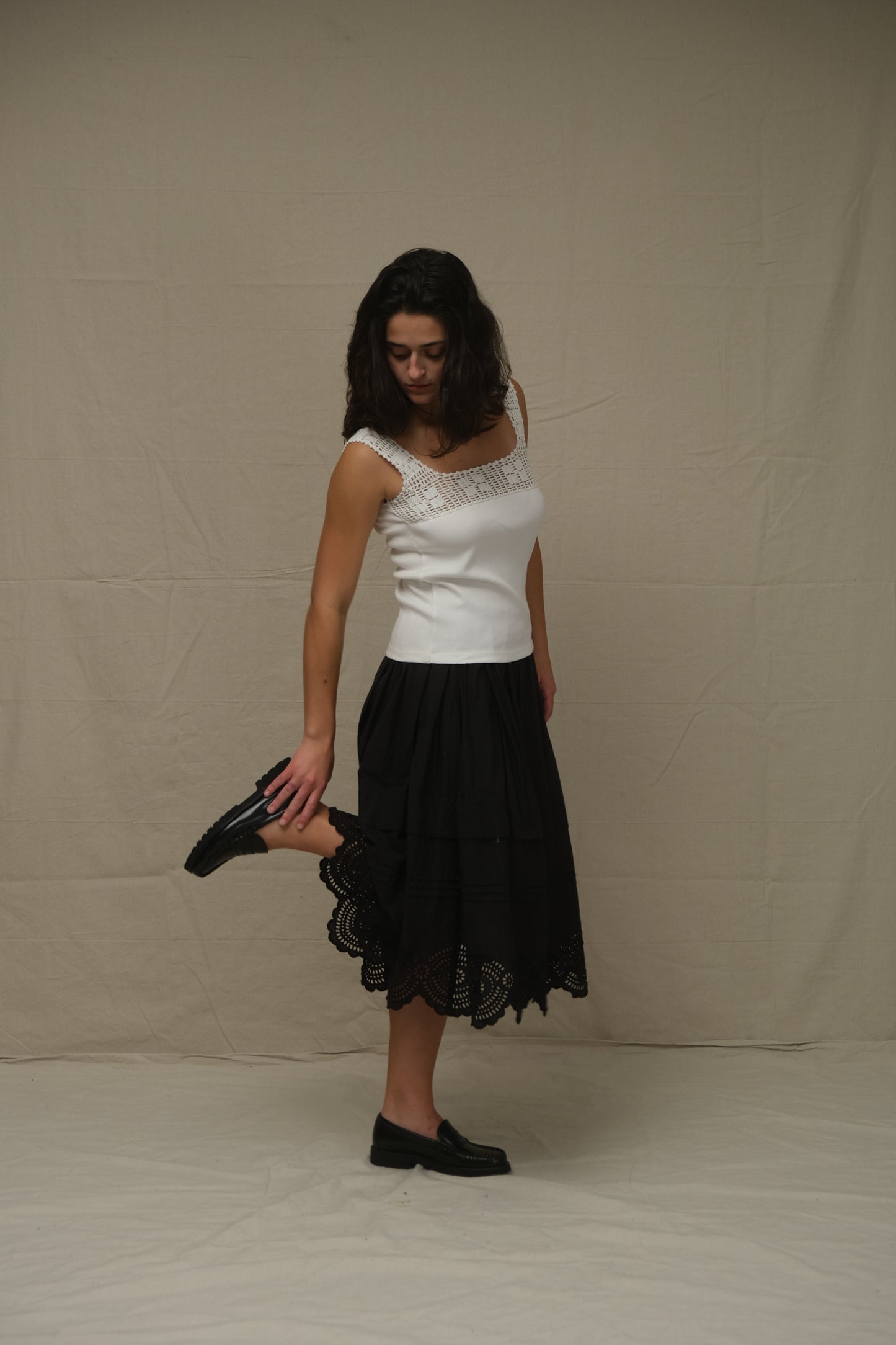 Woman wearing a black skirt and white top on a plain background