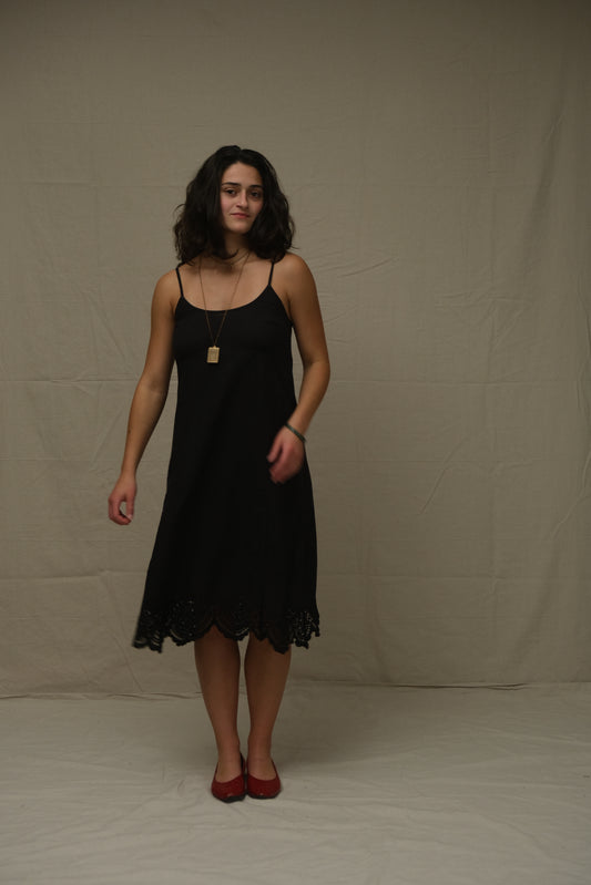 Woman in a black dress standing on a plain background