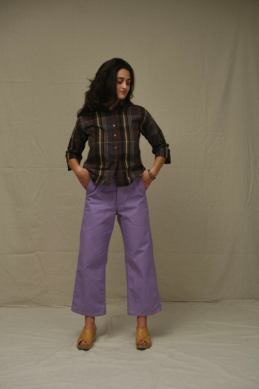 Woman wearing a plaid shirt and purple pants against a plain background