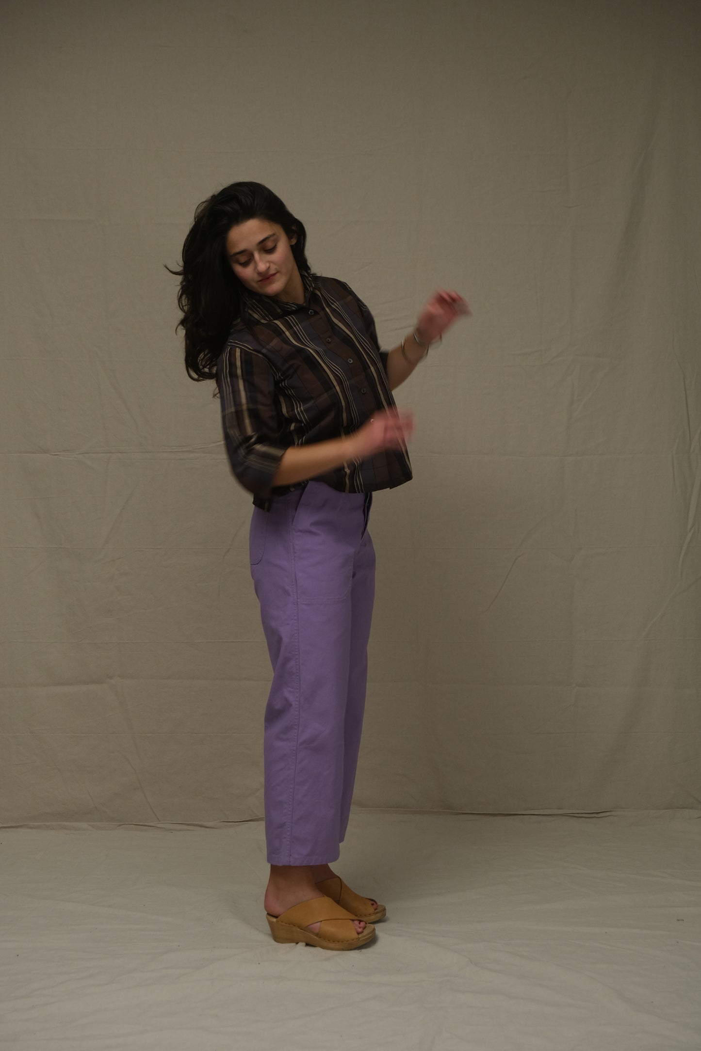 Person wearing a black shirt and purple pants on a plain background