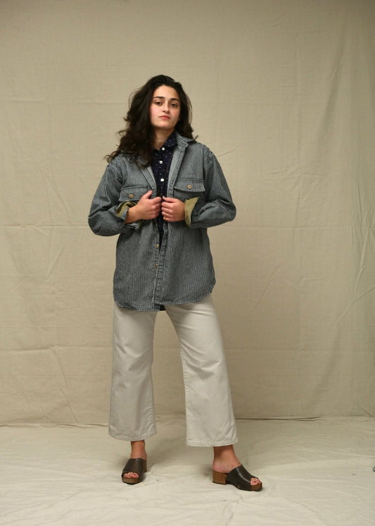 Person wearing a rr stripe jacket and white pants against a plain background
