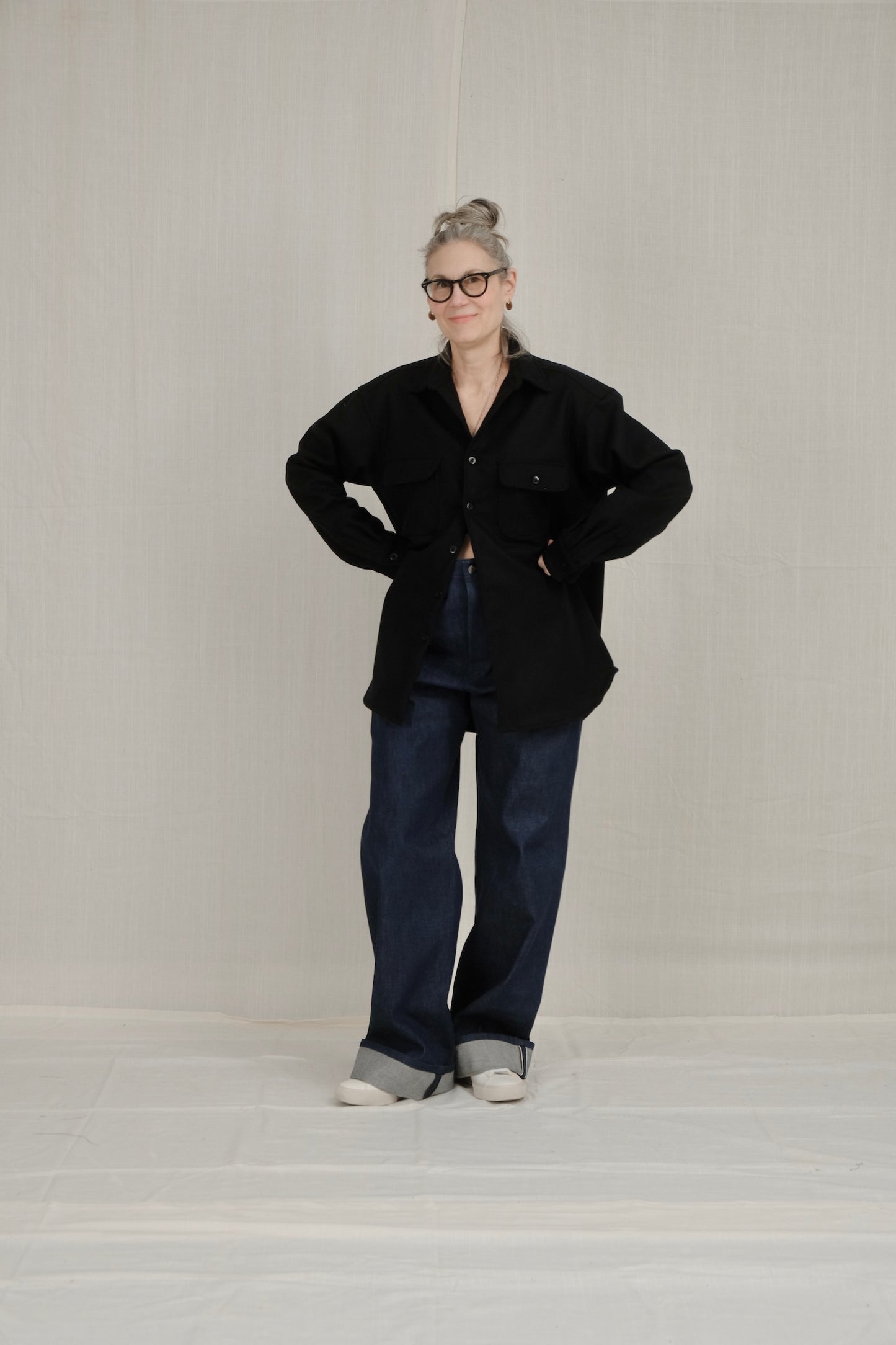 Person wearing a wool navy overshirt jacket and indigo selvage sailor pants on a plain background
