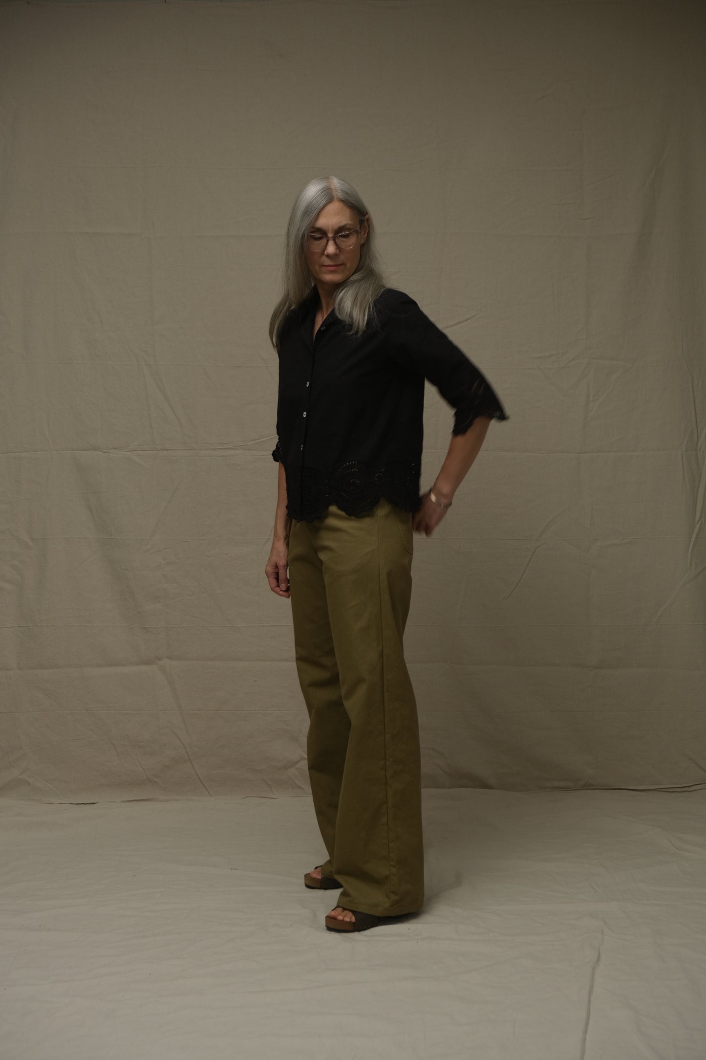 Person wearing a black shirt and green pants on a white background