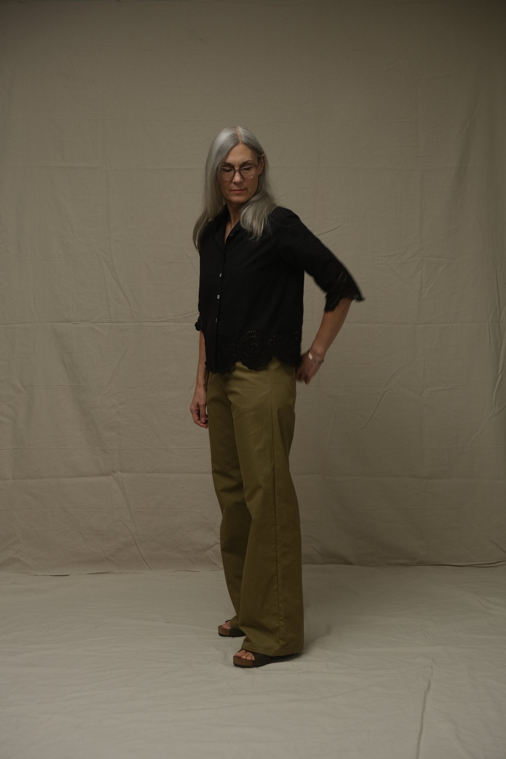 Person wearing a black shirt and green pants on a white background