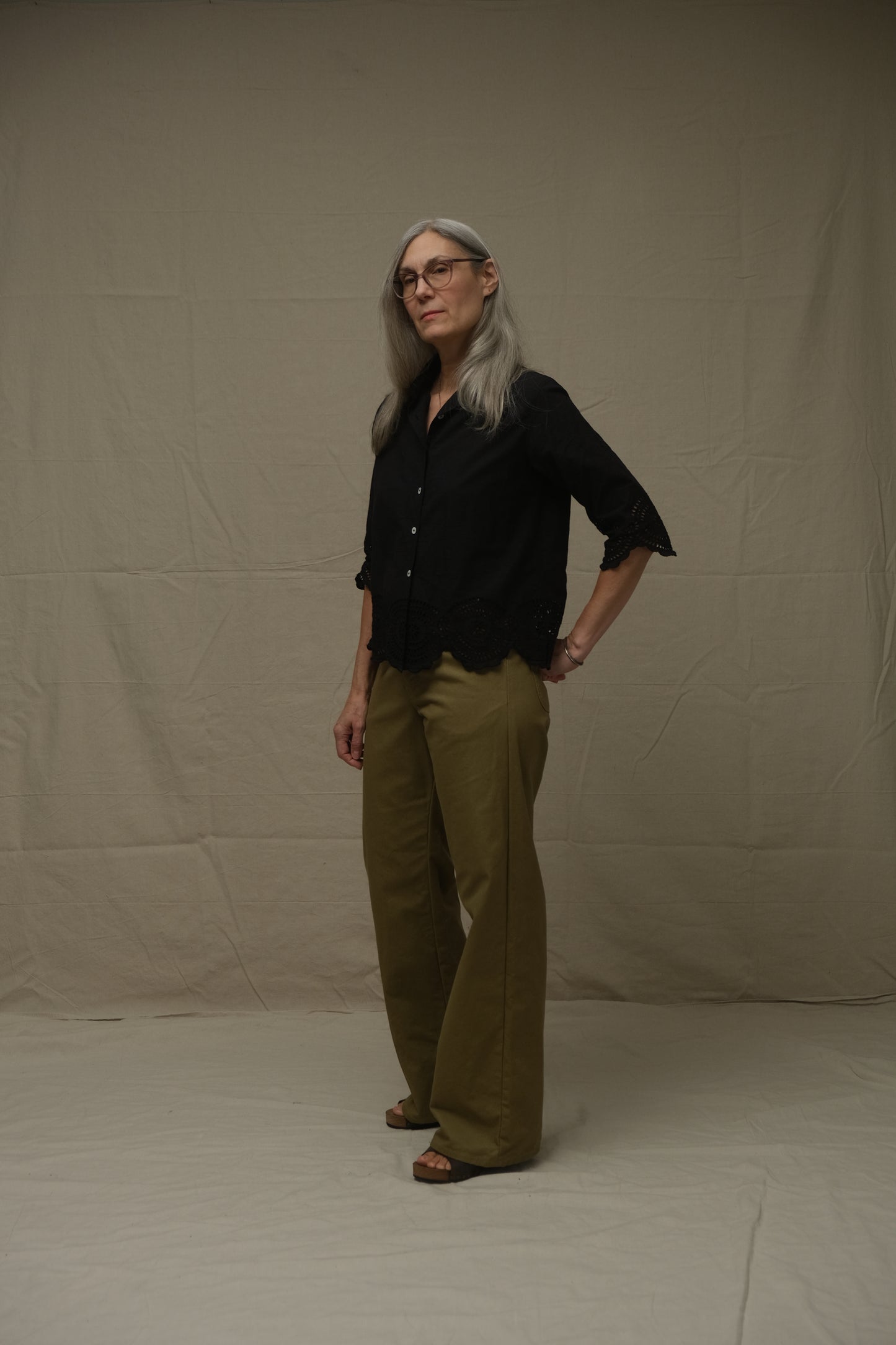 Person wearing a black shirt and green pants on a plain background