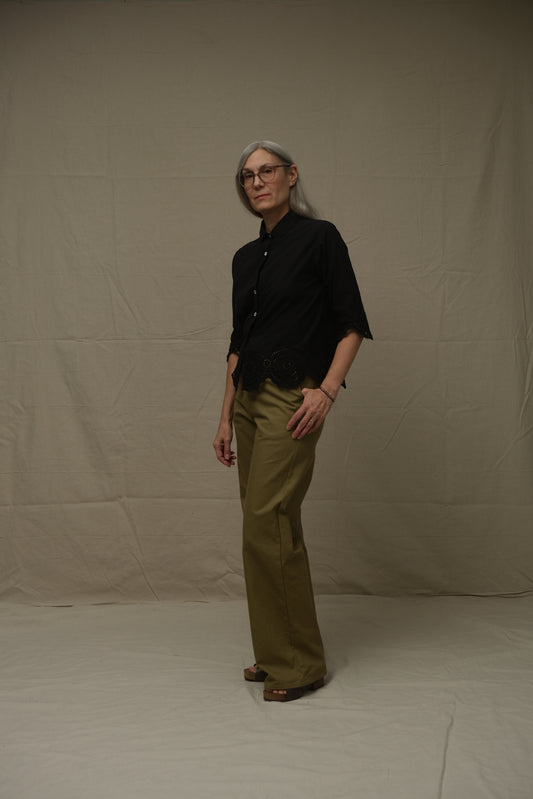 Person wearing a black shirt and green pants on a plain white background