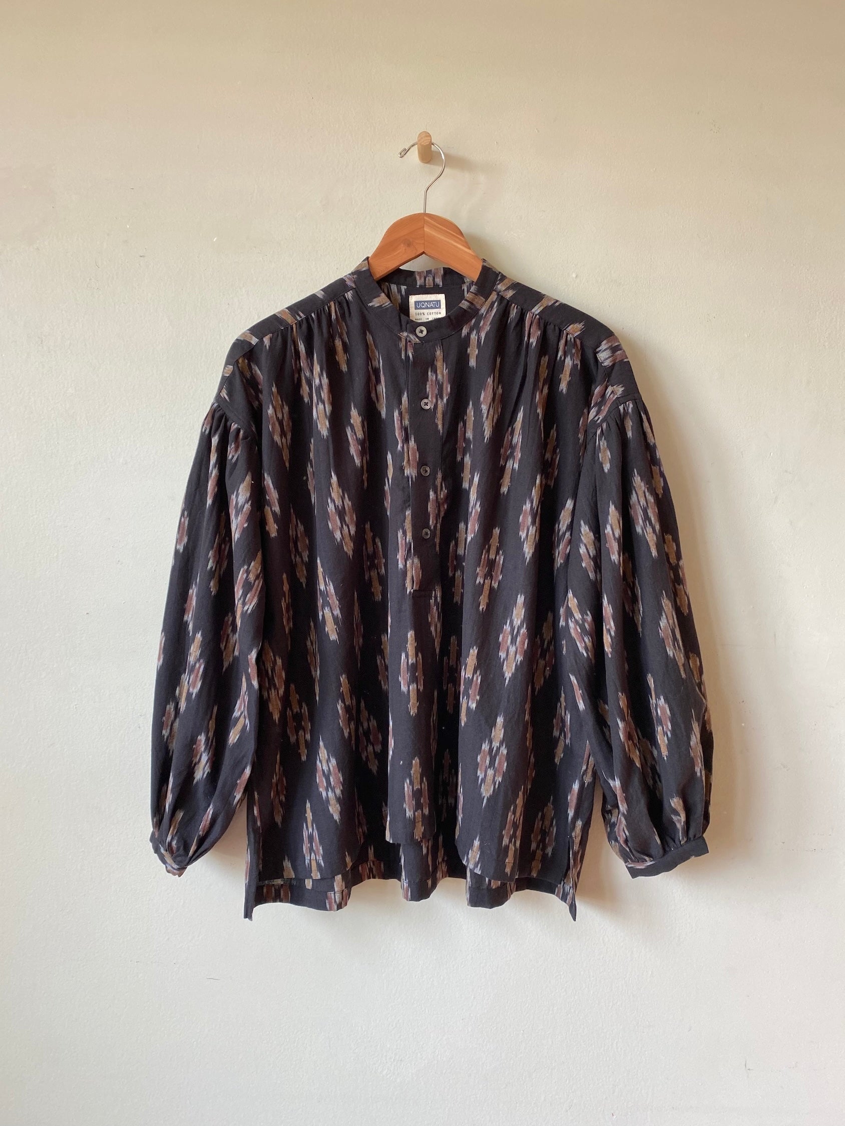 Patterned shirt on a hanger against a plain background