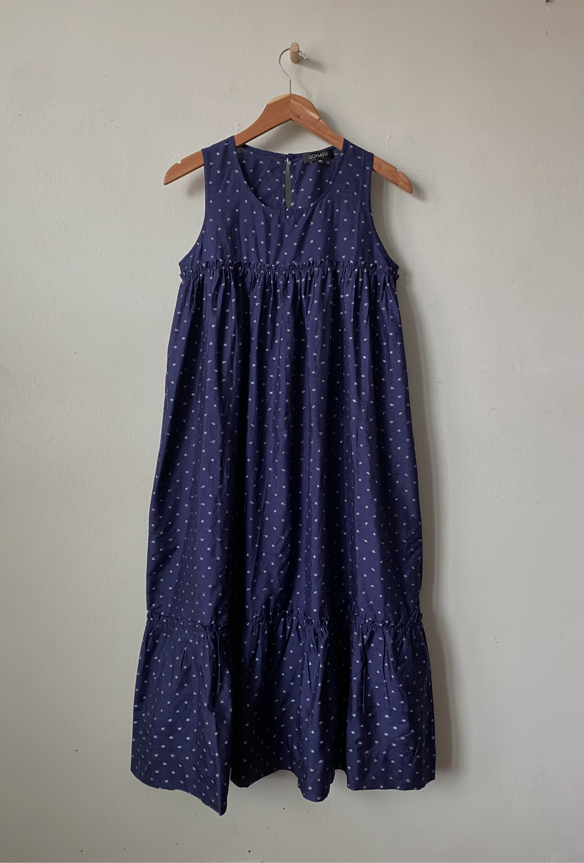 Navy blue dress with white polka dots on a hanger against a plain background