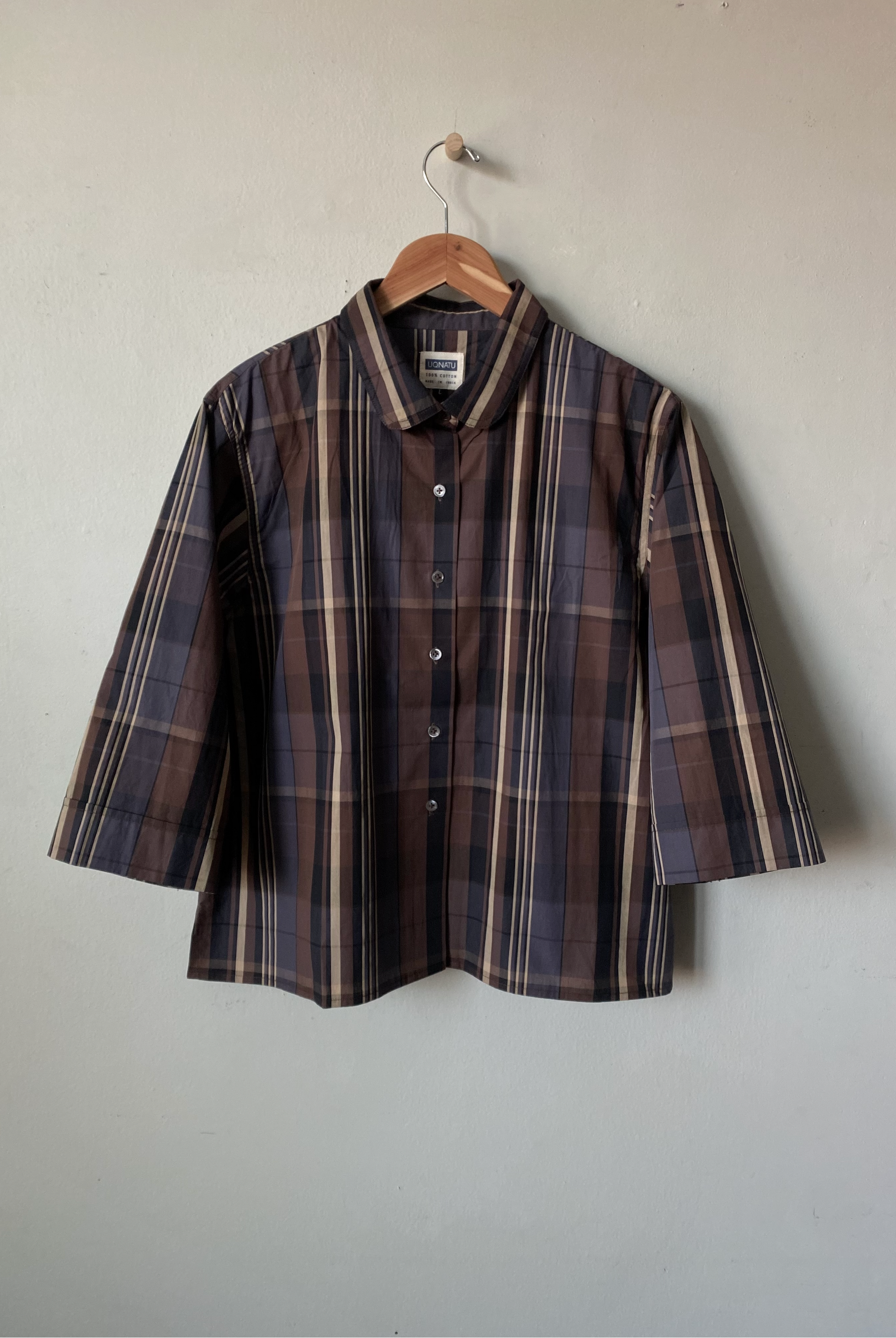 Plaid shirt on a hanger against a plain background