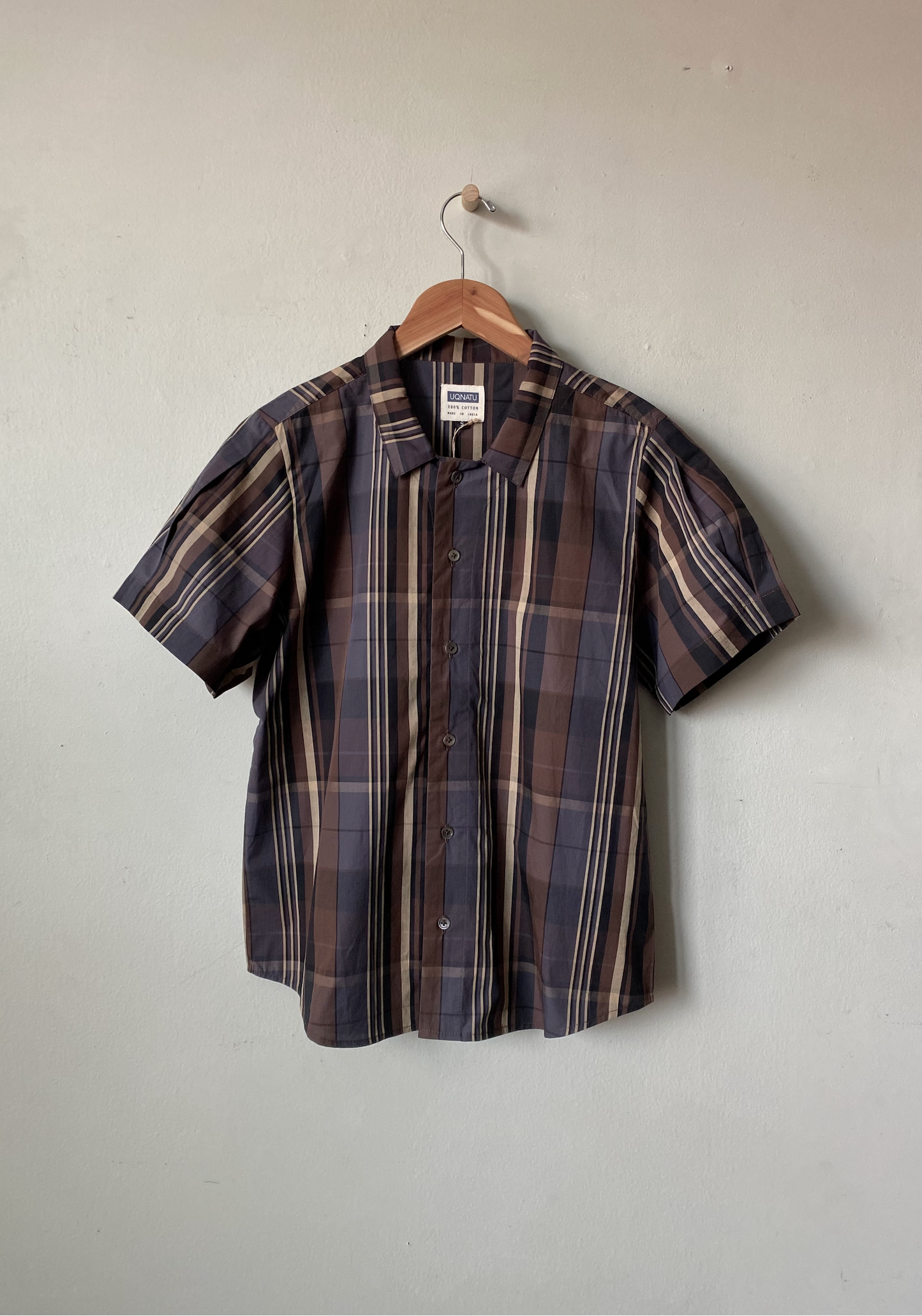Plaid short-sleeve shirt on a hanger against a plain background