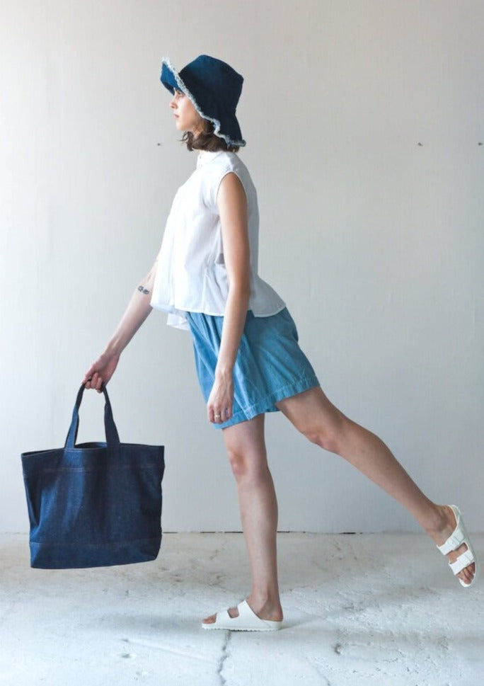 MODEL WEARING HAT HOLDING TOTE